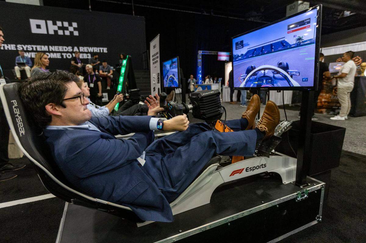 A person tries a sports car driving simulator in a trade show booth at eMerge Americas conference on April 20, 2023.