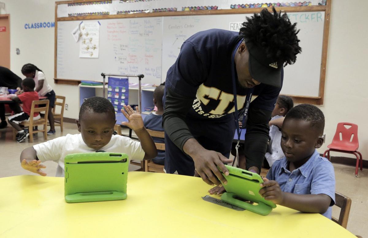 Camp counselor Vinton M. Lewis, center, works with a couple of students during a session at the FIU Summer Academy in Miami on July 24, 2018.