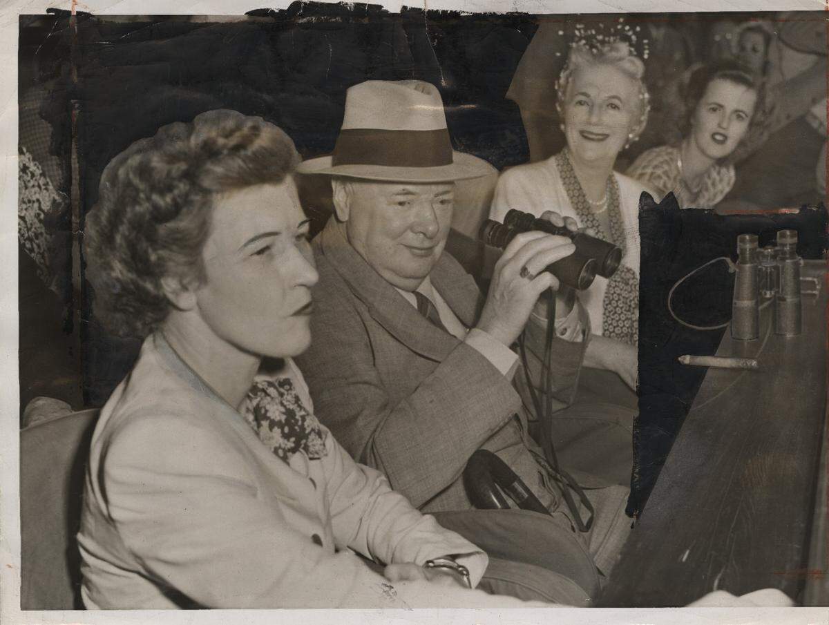 Winston Churchill parks his cigar on the ledge in front of him and keeps binoculars handy while watching the bangtails run at Hialeah Race Track in 1946.