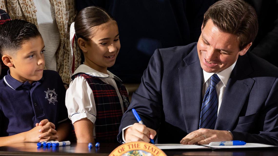 Gov. Ron DeSantis signs a bill to expand school vouchers across Florida during a press conference at Christopher Columbus High School on Monday, March 27, 2023, in Miami.