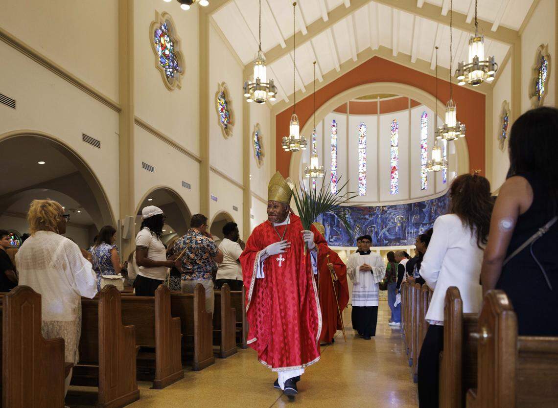 Bishop Pierre-André Dumas of Haiti walks down the side greeting parishioners after Palm Sunday mass on Sunday, March 29, 2026, at the Cathedral of St. Mary in Miami, Fla. The service began with the traditional blessing of the palms outside the cathedral followed by Mass.