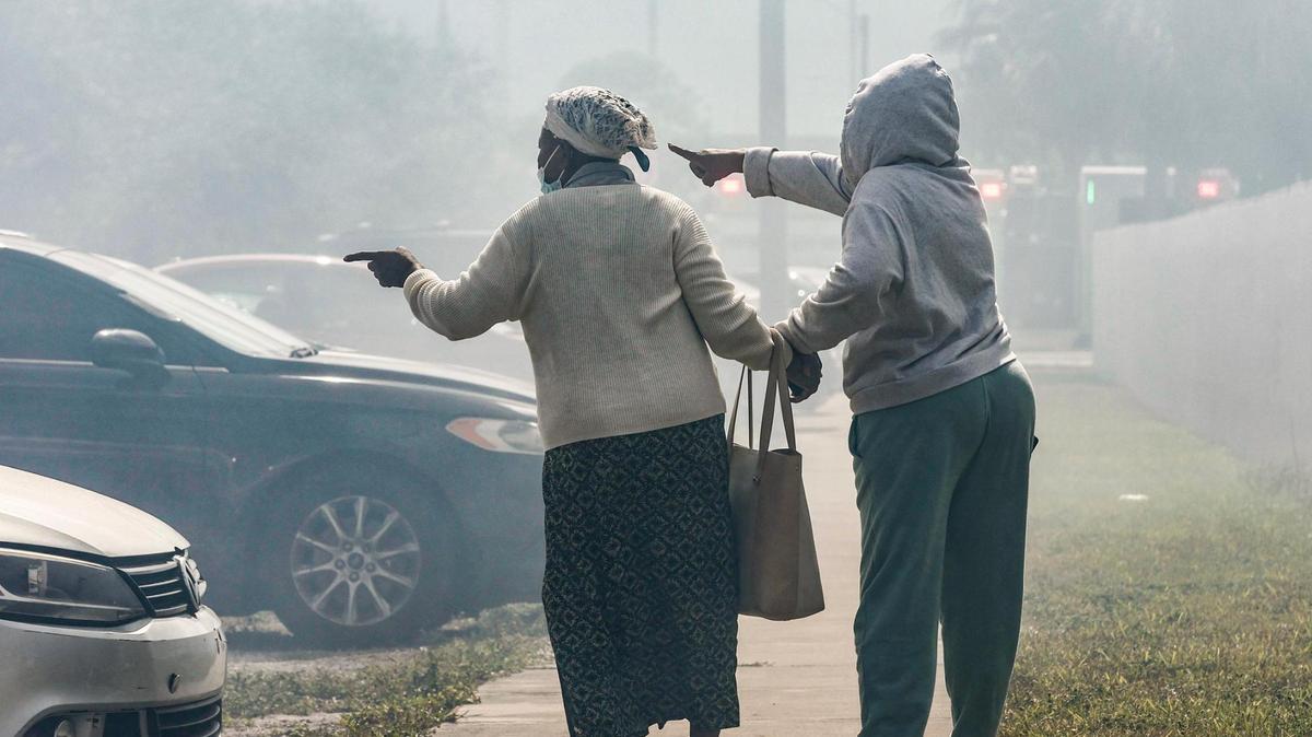 Francilia Jean, at left, is assisted as she points towards a fire that engulfs her two-story apartment building at 395 NW 177 Street on Saturday morning Saturday, January 28, 2023.