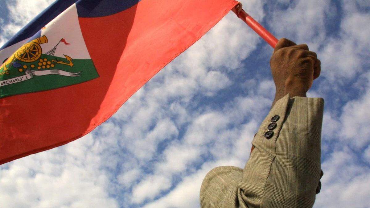 A man waves the flag of Haiti, whose president wants to hold elections in June despite unmitigated violence, kidnappings and insecurity.