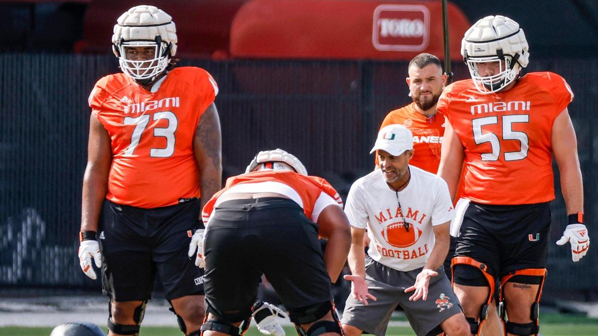 miami hurricanes offensive line coach Alex Mirabal works with offensive lineman Anez Cooper (73) and Jacob Lichtenstein (55) during football practice at the University of Miami’s Greentree Field on Thursday, March 9, 2023.