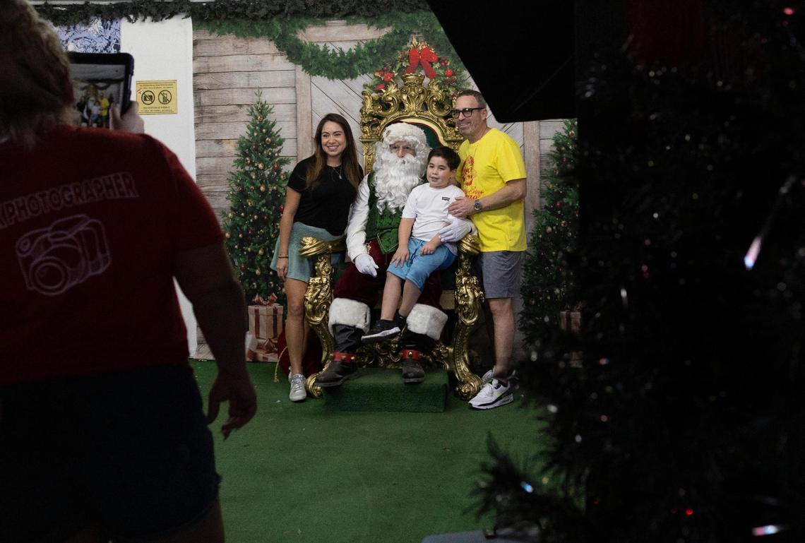 Veronica Krueger, left, her son, Drew, 6, and Matthew take a photo with Santa during the opening night of Santa’s Enchanted Forest on Friday, Nov. 11, 2022.