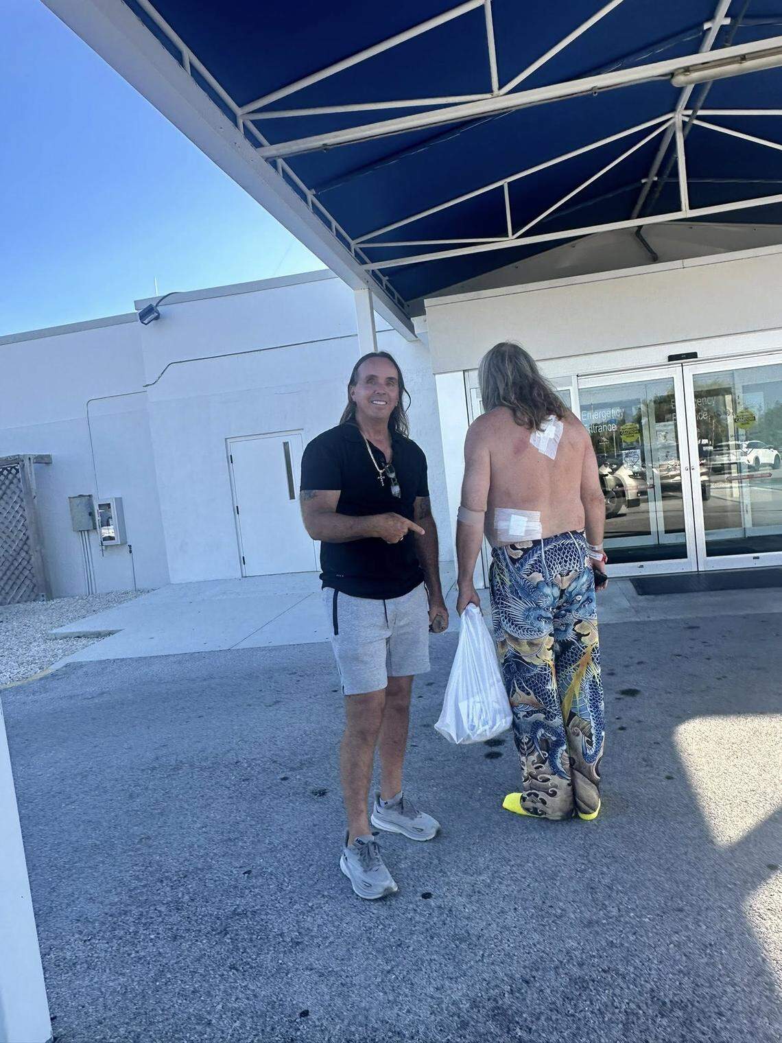 Gary Burchfield, owner of Gary the Carpenter in Key West, stands outside of the Lower Keys Medical Center with his employee, Joe Clements, who police say came to the aid of a colleague being attacked with a knife, and getting stabbed in the process. Clements is showing the the two stab wounds he received.