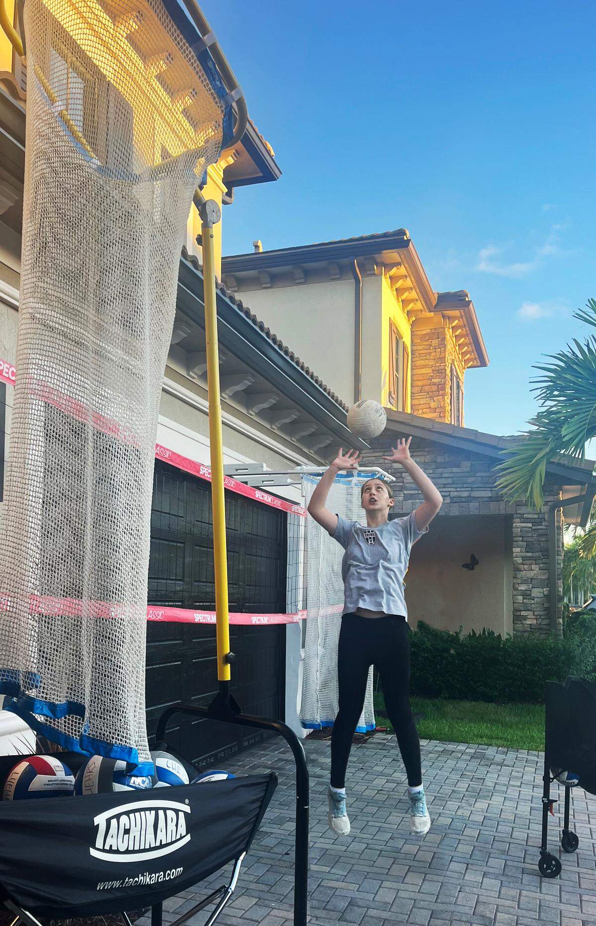 Emma Luehrs, a talented eighth-grader and starting setter for the North Broward Prep volleyball team, trains in the driveway of her house.