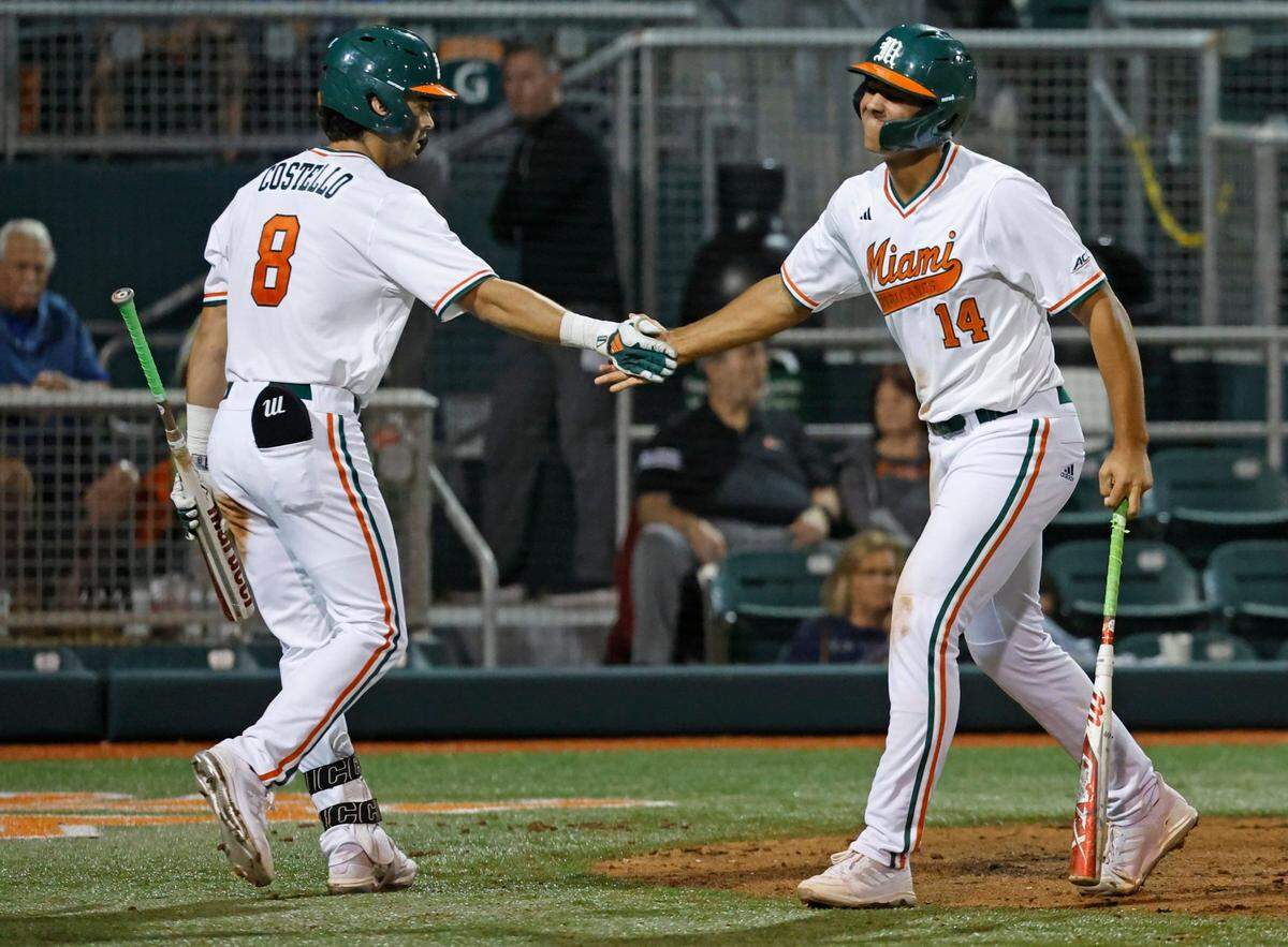 Miami Hurricanes outfielder Lucas Costello (8) meets with infielder Daniel Cuvet (14) after Cuvet scores in the 6th inning against the Florida Gulf Coast University at Alex Rodriguez Park at Mark Light Field in Coral Gables, Florida on Wednesday, February 28, 2024.