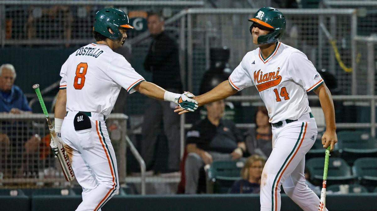 Miami Hurricanes outfielder Lucas Costello (8) meets with infielder Daniel Cuvet (14) after Cuvet scores in the 6th inning against the Florida Gulf Coast University at Alex Rodriguez Park at Mark Light Field in Coral Gables, Florida on Wednesday, February 28, 2024.