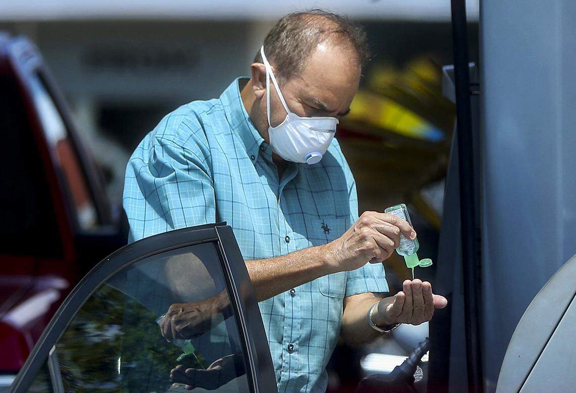 A consumer wears a mask and uses hand sanitizer for protection against the coronavirus at a Chevron gas station in West Miami on Wednesday, April 1, 2020.