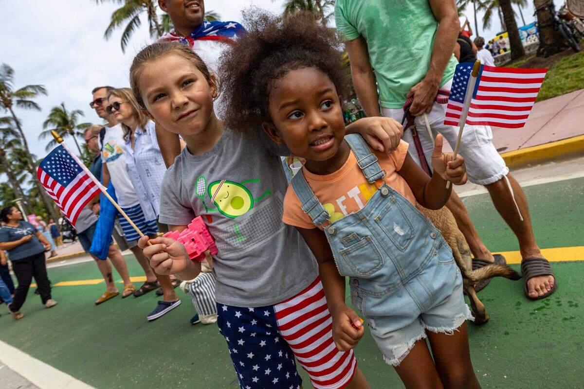 Sebastian, 6, embraces his friend Brooklyn, 5, as they watch parade participants march and drive past during the 16th Annual Veterans Day Parade off Ocean Drive on Monday, Nov. 11, 2024, in Miami Beach, Fla.
