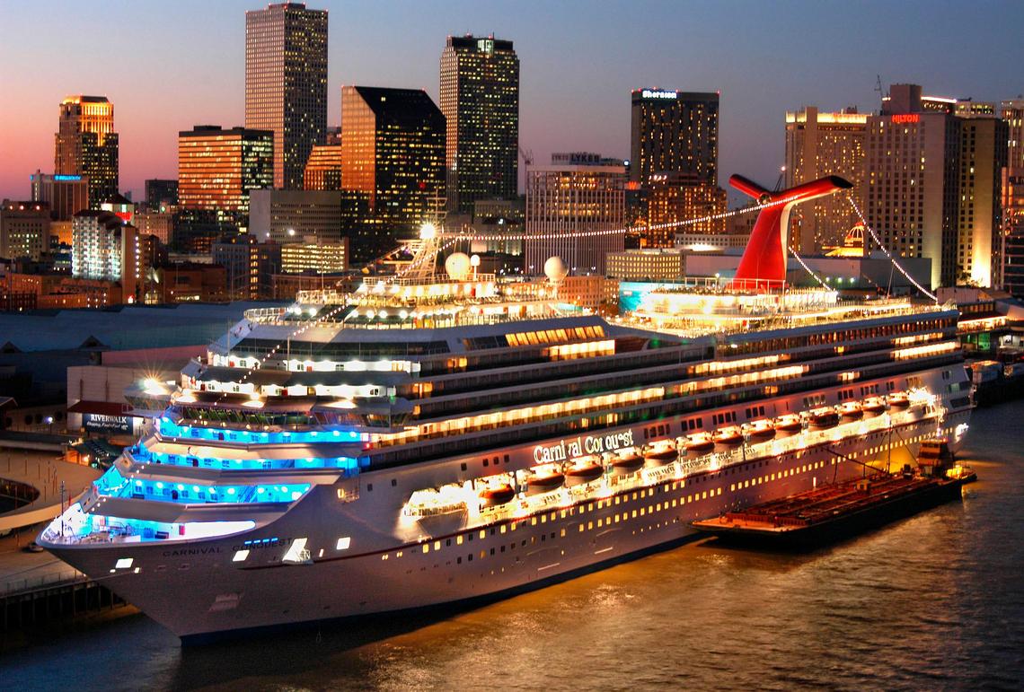 The Carnival Conquest, a new 110,000-ton cruise ship is aglow against the New Orleans skyline Tuesday, Nov. 12, 2002. Twenty years later, on Friday, March 11, 2022, Carnival celebrated its 50th anniversary aboard the Conquest docked in PortMiami. (AP Photo/Carnival Cruise Lines, Andy Newman)