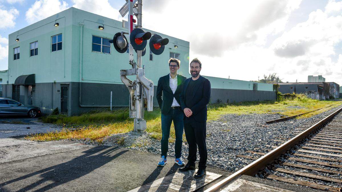 Architects Alberto Veiga, left, and Fabrizio Barozzi stand at the Florida East Coast Railway tracks in front of the site in the Little River-Little Haiti neighborhood where they will design a new building for Oolite Arts. The nonprofit group announced it has hired the award-winning, Barcelona-based architects to design a complex housing artists’ studios, a theater, exhibition space and a “maker space.”