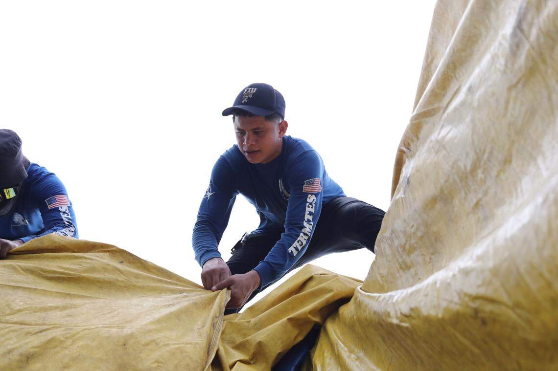 On a sweltering day, an employee of SPC Termites wraps a tarp around a Miami Springs home to help eliminate the pests on July 5, 2023.