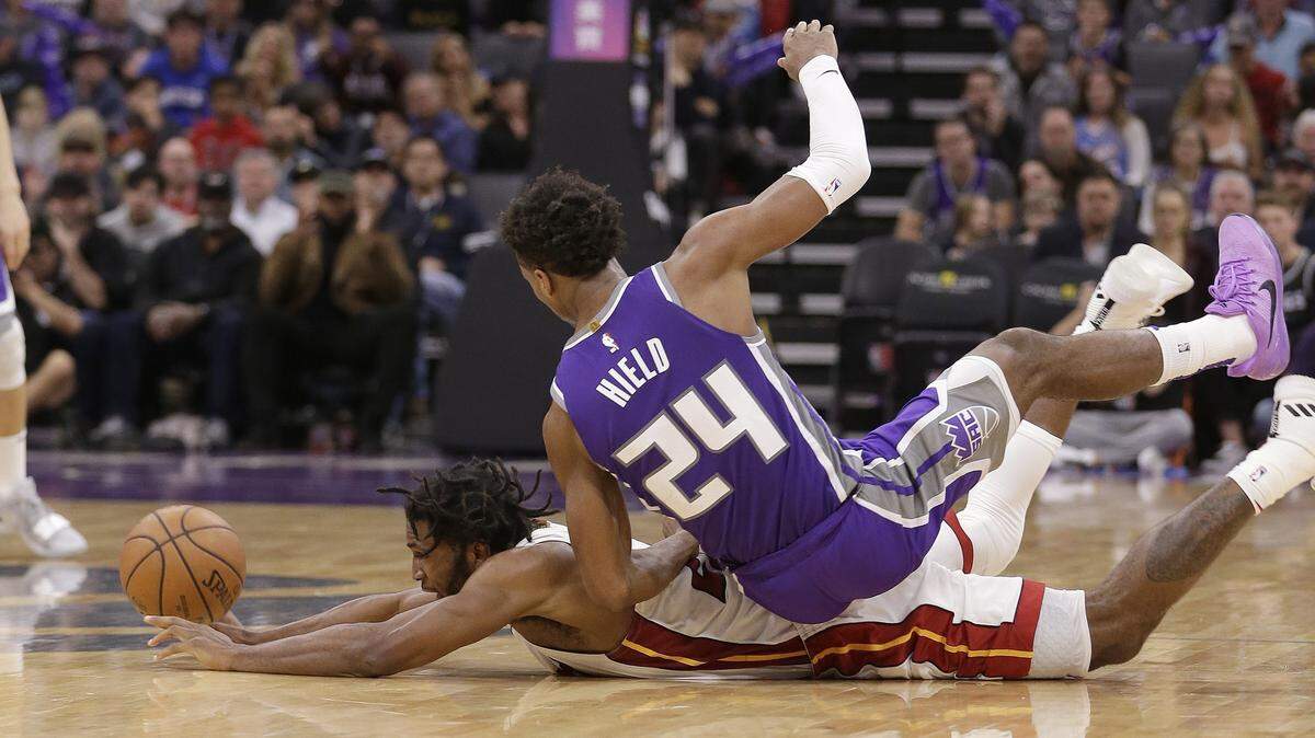El escolta de los Kings Buddy Hield cae sobre el armador del Heat Justise Winslow, este viernes en Sacramento.