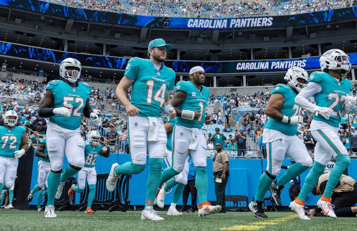 Miami Dolphins quarterback Tua Tagovailoa (1) takes the field with teammates before an NFL football game against the Carolina Panthers on Sunday, Oct. 5, 2025, in Charlotte, N.C.