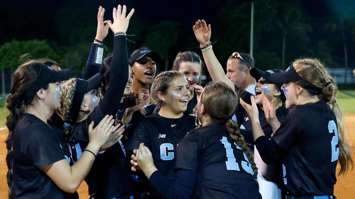 Coral Springs Charter teammates celebrate with Stephanie Basso (22), at center, after she receives the game MVP award after the team defeats Western in the BCAA Big 8 softball championship game at Pompano Beach Community Park in Pompano Beach on Thursday, April 27, 2023.