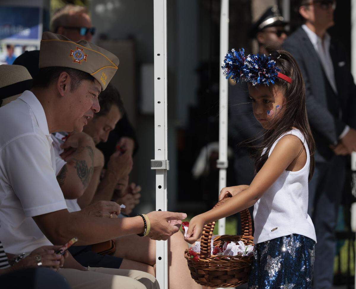 Tala Shaal, girl scout from Miami Beach, right, gives a flower pin to Lt. Col. Jackie Tam, Veterans of Foreign Wars 3559 commander, during a Memorial Day Commemoration on Monday, May 25, 2026, at Miami Beach Police Headquarters in Miami Beach, Fla. 