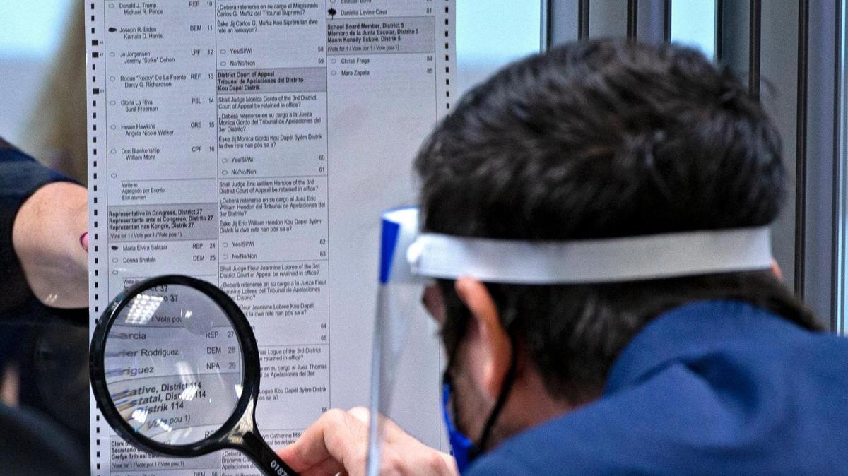 Steve Simeonidis, abogado y presidente del Partido Demócrata d Miami-Dade, estudia una boleta en un recuento manual en la carrera por el Distrito 37 al Senado estatal, en el Departamento de Elecciones de Miami-Dade el 12 de noviembre de 2020..