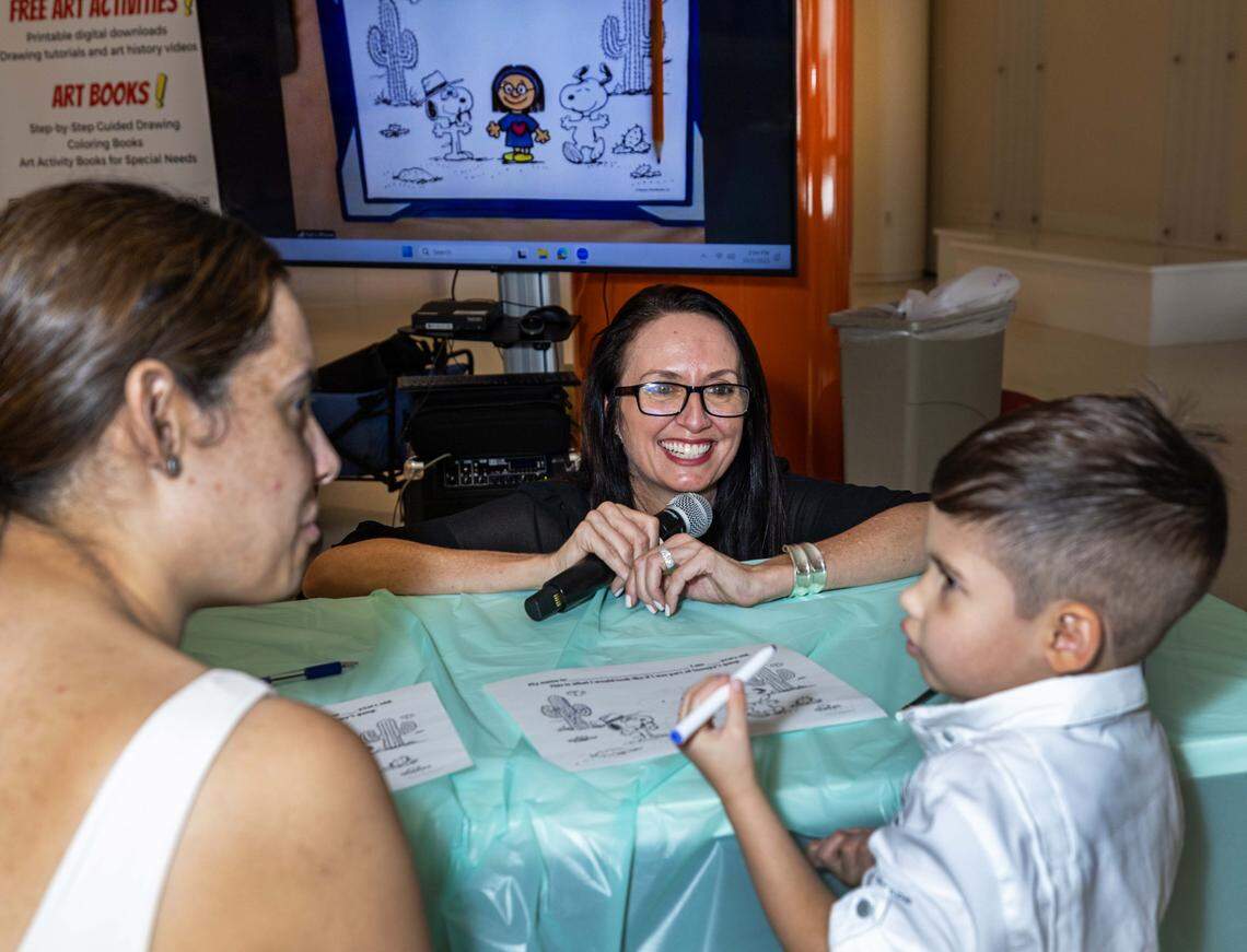 Riley Alvarez, 3, draws next to his mom, Elischa Ramirez, while being instructed by Comic Kids nonprofit co-founder Kat-Barrow-Horth during a Peanuts PaintFest event as they celebrate the "Peanuts" comic strip turning 75 at Nicklaus Children's Hospital Main Campus on Thursday, October  2, 2025, in Miami, Fla.