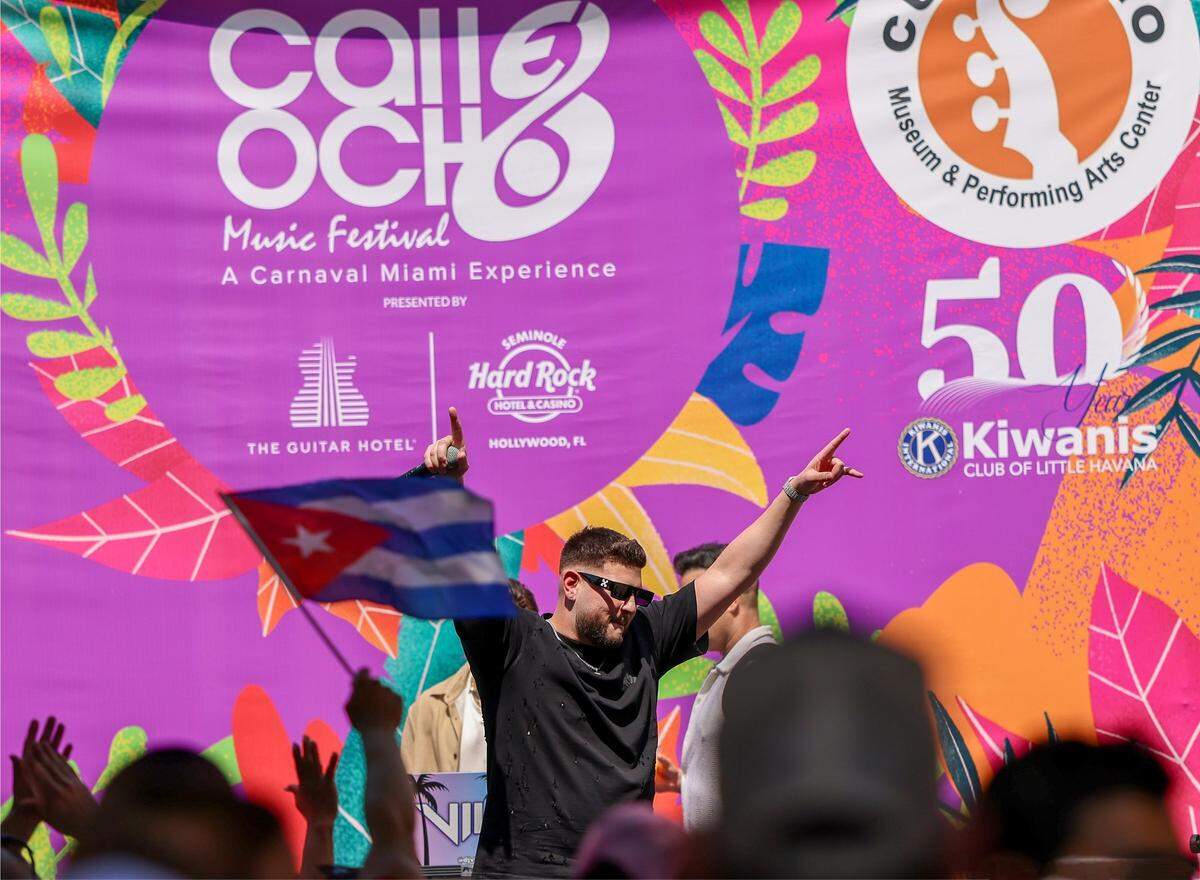 Performance artist “El Yuma”, center, exits the stage as the crowd reacts with waved arms and flags.