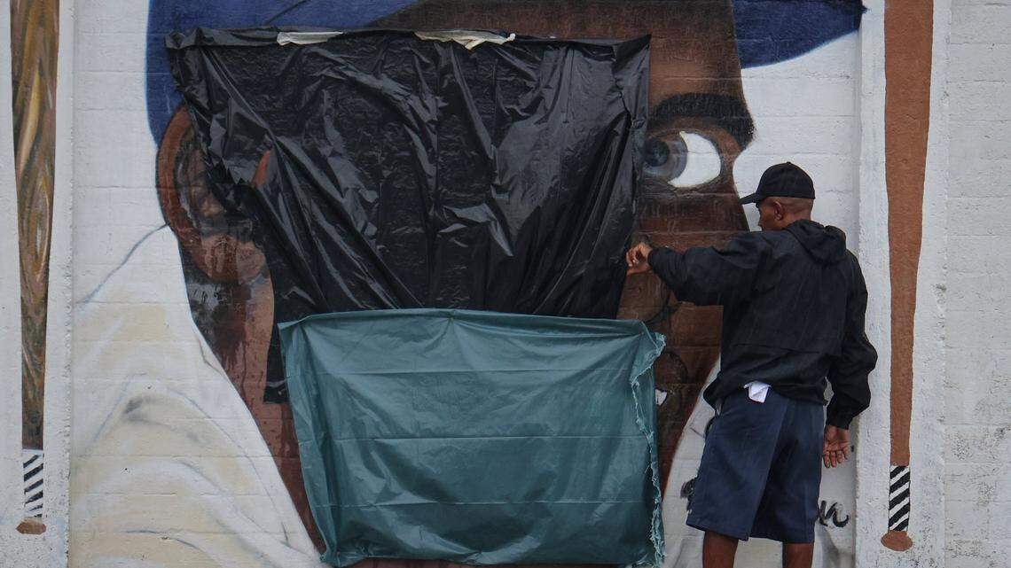 An unidentified man with the Downtown Development Authority takes a close look at the mural of Jackie Robinson after it was defaced with a swastika and Jim-Crow era racial epithet on Tuesday, June 3, 2025, at Dorsey Park in Miami, Florida. Robinson was the first Black baseball player to integrate Major League Baseball in 1947 when he signed with the Brooklyn Dodgers.