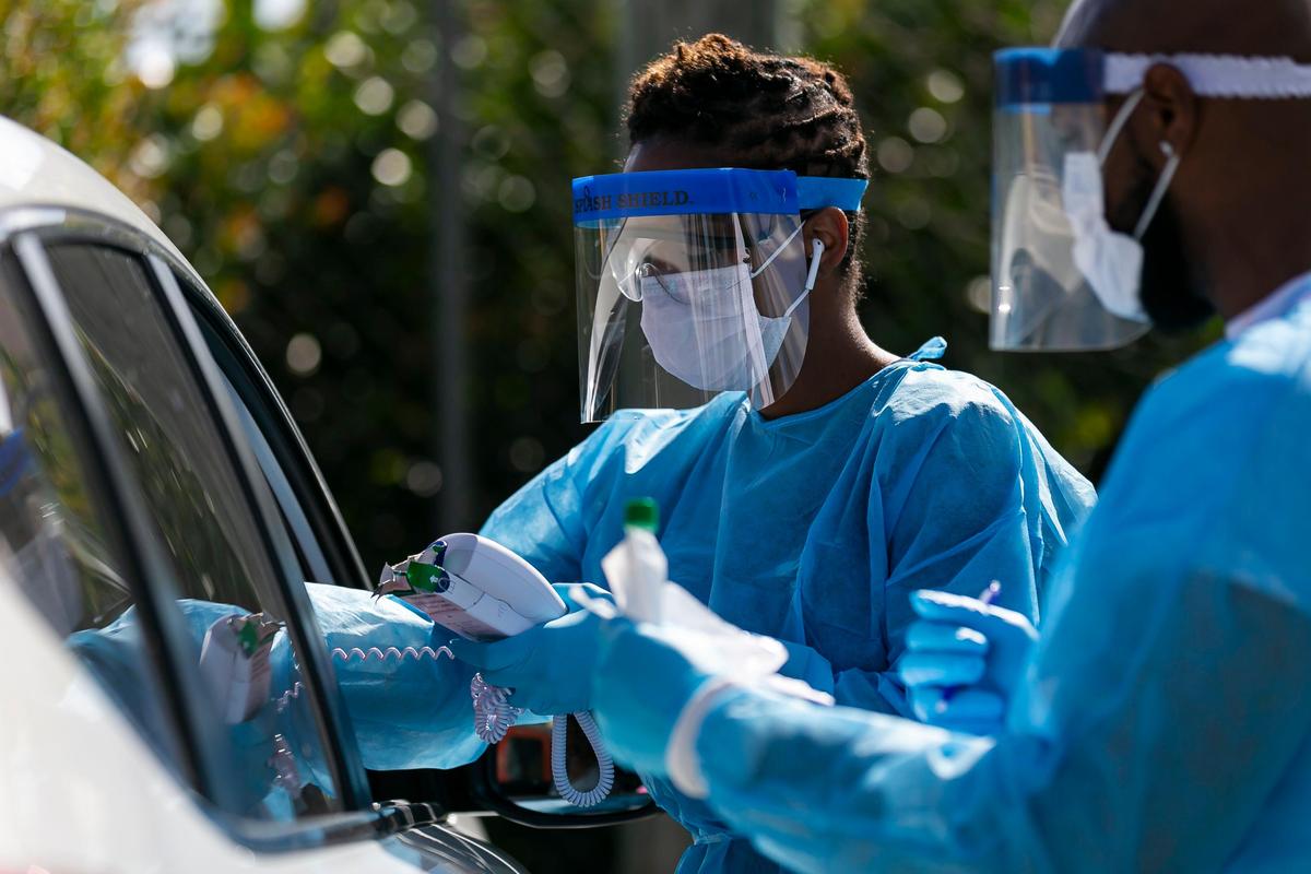 A FoundCare staff member administers a coronavirus test to people in a drive-through at the FoundCare parking lot in West Palm Beach, Florida on Tuesday, March 17, 2020.