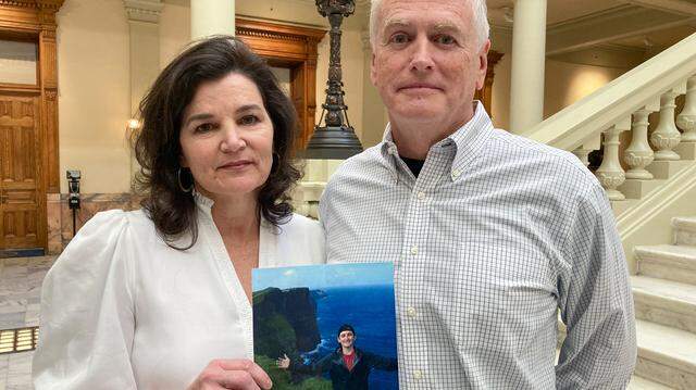 Dana and John Pope pose with a photo of their son Ethan, following a news conference at the Capitol in Atlanta, Thursday, Oct. 27, 2022.