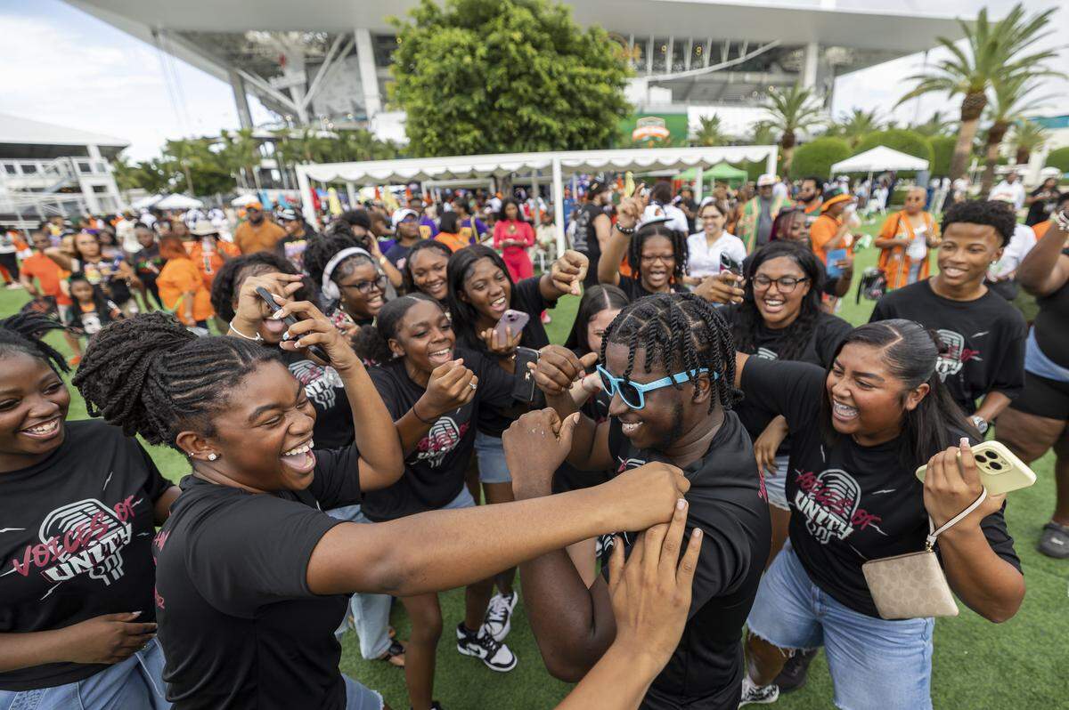Michael Bartley, center, a choir teacher at Palm Beach Lakes Community High School, dances as his students react during a fan festival before the Orange Blossom Classic football game between the Florida A&M Rattlers and the Howard Bison at Hard Rock Stadium on Saturday, Aug. 30, 2025, in Miami Gardens, Fla.