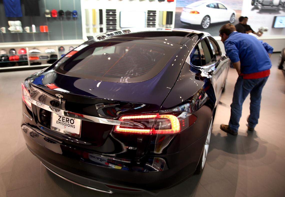 In this file photo from Feb. 19, 2014, a visitor to the Tesla Motors showroom looks at a vehicle at the Dadeland Mall location. A new showroom in Kendall, about four miles to the south, joins this one and is to open in late 2026 as part of the Palms at Town & Country property.
