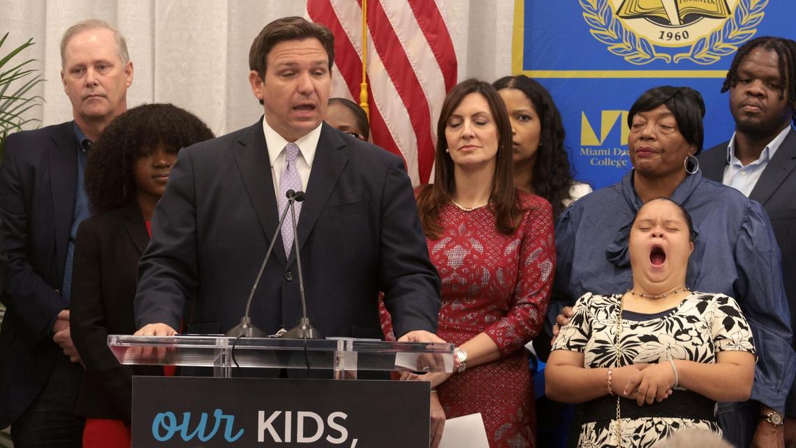 On Tuesday, April 12, 2022, Gov. Ron DeSantis, left, gives his opening remarks before he signed a bill that financially benefits more people who care for needy children and helps additional children who were in the foster care system attend a state college or university. The bill signing was at Miami Dade College Wolfson Campus in Miami, Florida.