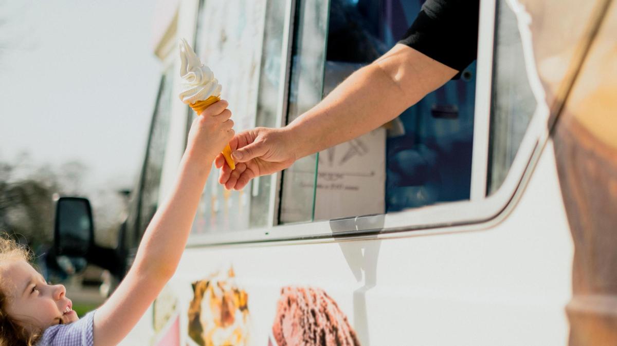 Una niña recibe su postre de un camión de helados.