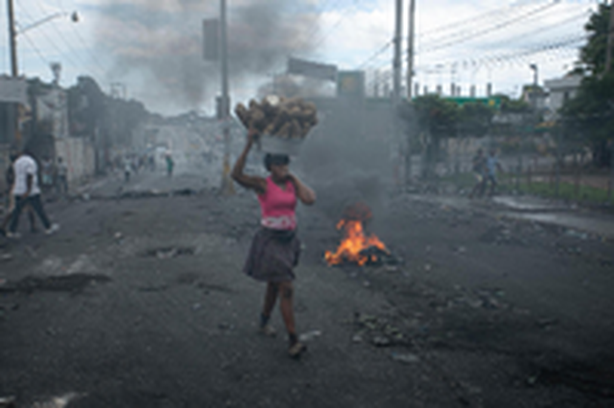 A street vendor walks past a barricade set up by demonstrators to protest against fuel price hikes and to demand that Haitian Prime Minister Ariel Henry step down in Port-au-Prince, Haiti, Monday, Sept. 19, 2022.