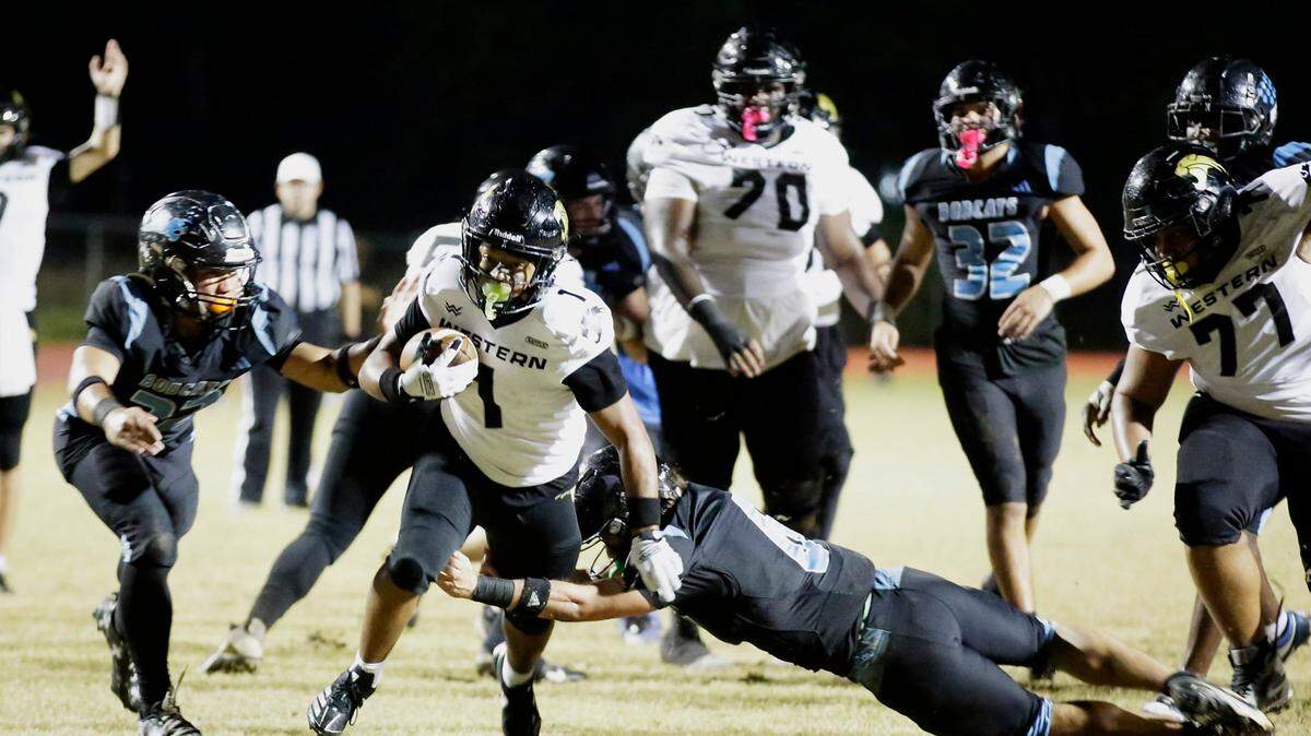Western Wildcats running back Robert Ortega (1) fights off a tackle by West Broward Bobcats defenders during football game on Friday, November 1, 2024 at Everglades HS in Miramar. Andrew Uloza / for Miami Herald