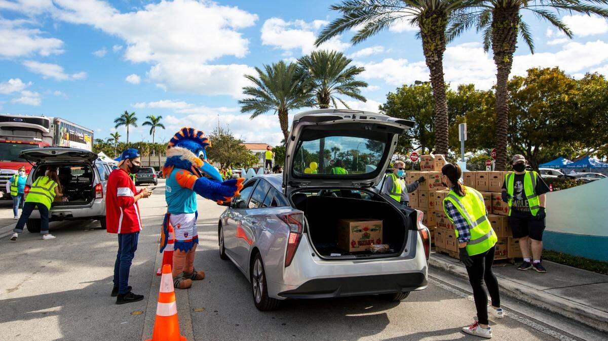 Volunteers and staff stock the trunks of guests in line of the contactless drive-thru delivery system hosted by Miami Children’s Museum and Farm Share in 2021