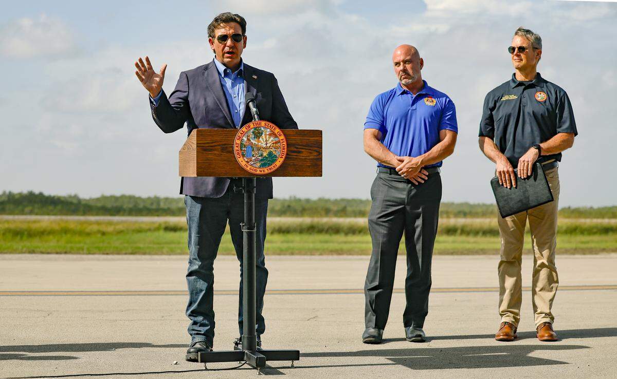Governor Ron DeSantis speaks to reporters during a press conference on the airplane runway of Alligator Alcatraz in Ochopee , Florida on Friday, July 25, 2025. Next to the governor is Florida Department of Financial Services Chief Financial Officer Blaise Ingoglia and Florida State Board of Immigration Enforcement Executive Director Larry Keefe.