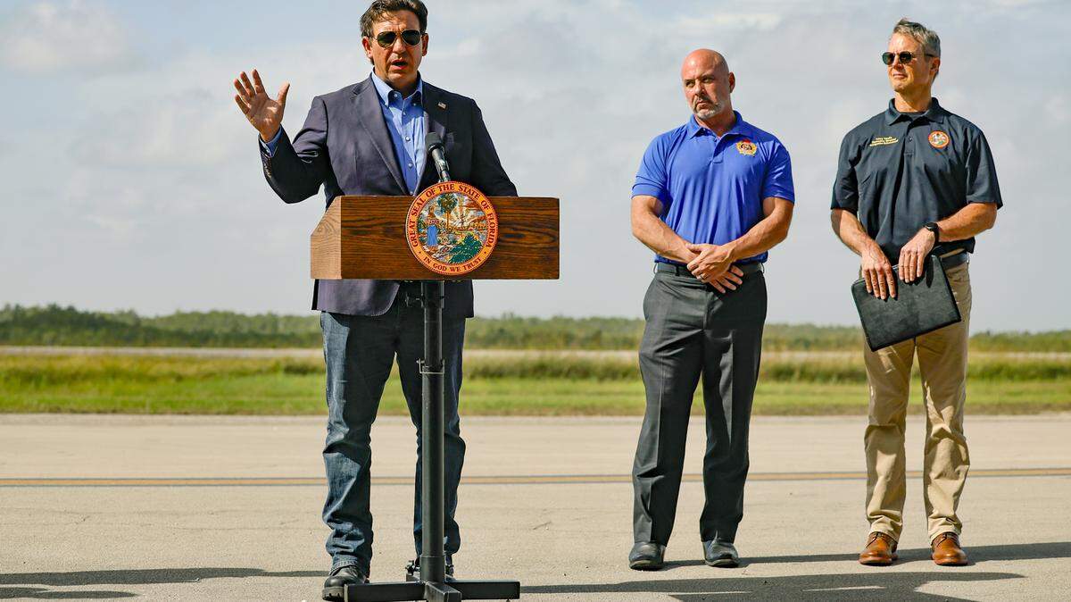 Governor Ron DeSantis speaks to reporters during a press conference on the airplane runway of Alligator Alcatraz in Ochopee , Florida on Friday, July 25, 2025. Next to the governor is Florida Department of Financial Services Chief Financial Officer Blaise Ingoglia and Florida State Board of Immigration Enforcement Executive Director Larry Keefe.