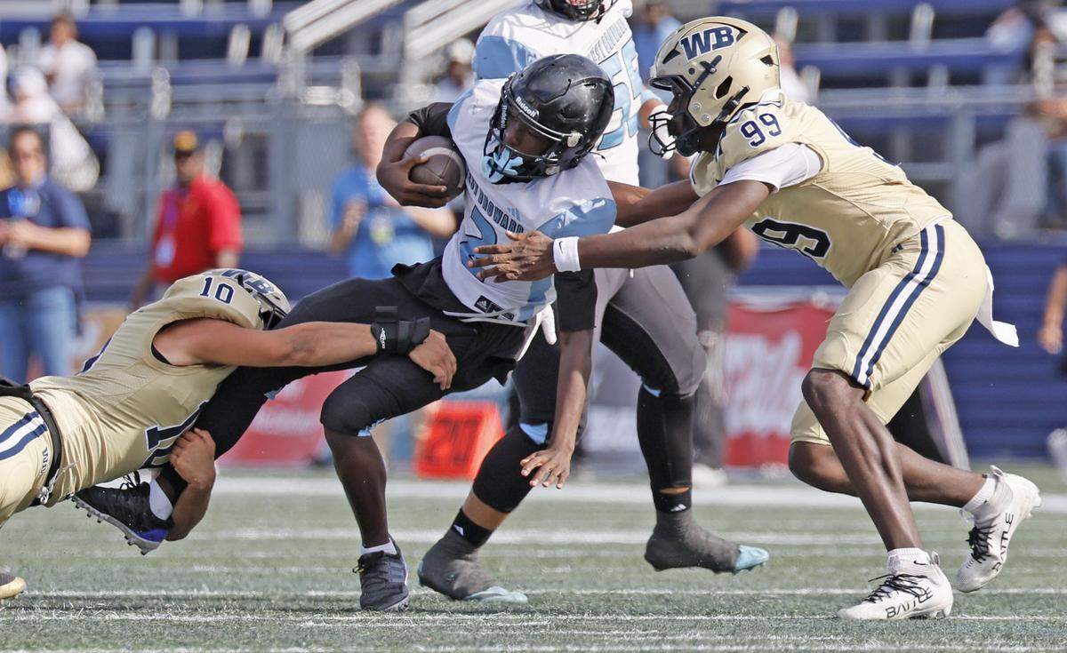 West Broward Bobcats quarterback Brandin Mincy (2) is sacked by West Boca Raton Bulls defenders Maxwell Reid (10) and Xavier Reid (99) during their Class 6A, Region 3 State Championship football game at FIU's Pitbull Stadium in Miami, Florida on Friday, December 12, 2025.