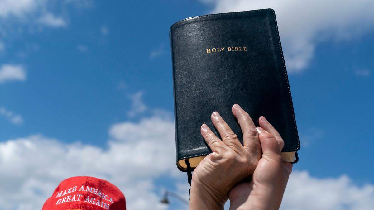 In March, a supporter of former President Trump raises a Bible across from Mar-a-Lago in Palm Beach.