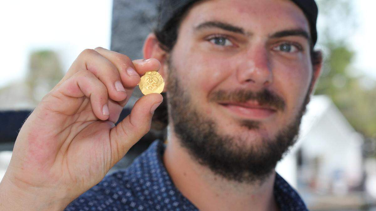 Zach Moore, a diver and engineer for Mel Fisher’s Treasures in Key West, holds the rare gold coin he found July 16, 2021, while searching the wreck of a Spanish galleon that sank in 1622.