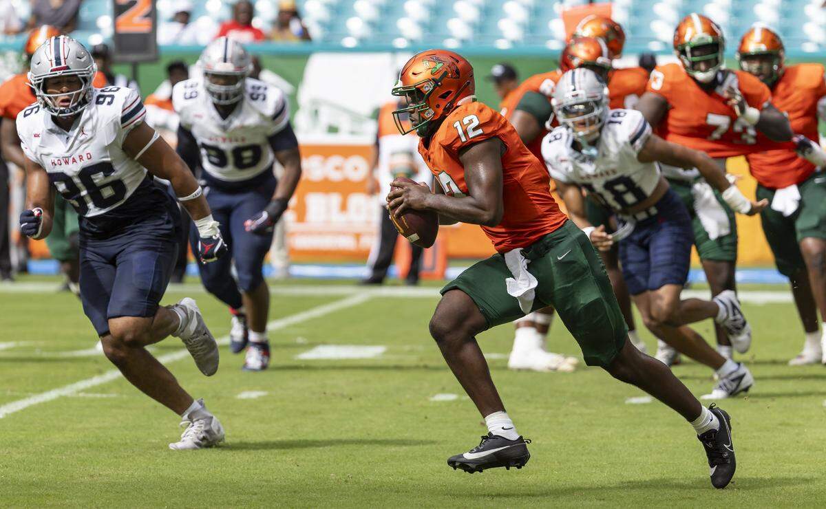 Florida A&M Rattlers quarterback RJ Johnson (12) runs with the ball as Howard Bison defensive lineman Keion Mitchell (96) defends in the first half of their Orange Blossom Classic football game at Hard Rock Stadium on Saturday, Aug. 30, 2025, in Miami Gardens, Fla.