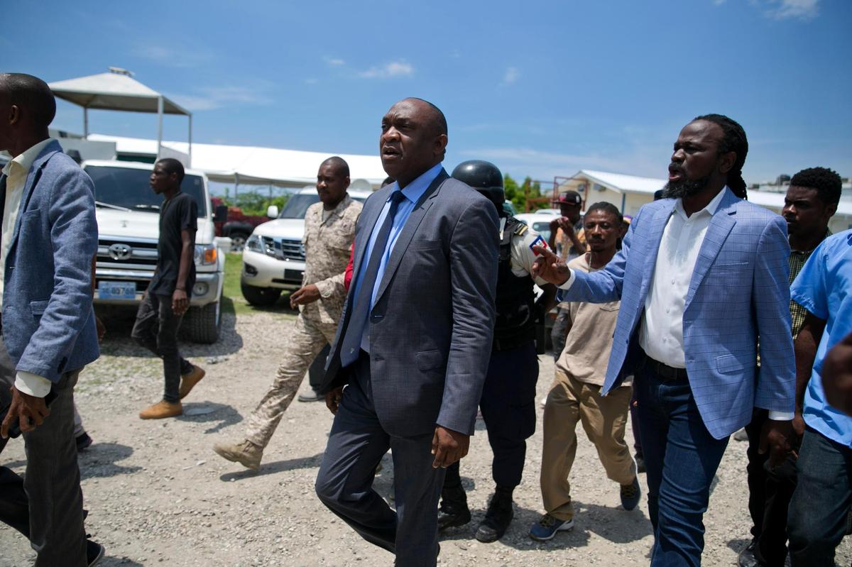 In this file photo, then-opposition’s senators Youri Latortue, center, walks with Antonio Cheramy, right, toward the parliament building before a vote to ratify designate Prime Minister Fritz William Michel, in Port-au-Prince, Haiti, Wednesday, Sept. 11, 2019. Michel would and his cabinet would fail to win ratification.