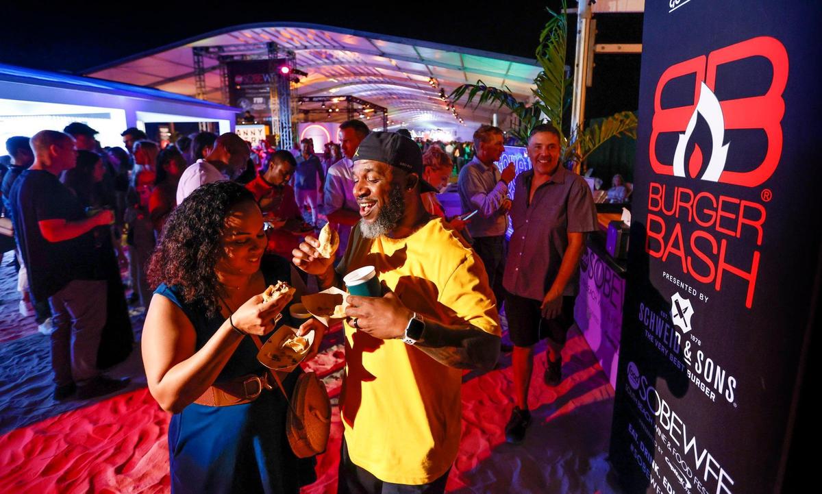 Dana and Efren Johnson try out a couple of burgers during the Burger Bash at the South Beach Wine & Food Festival on the sand by the Ritz Carlton in Miami Beach, Florida on Thursday, February 23, 2023.