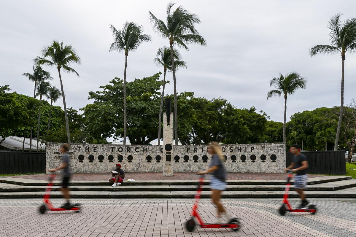 Riders scooter past the non-functional Torch of Friendship in downtown Miami on Saturday, November 7, 2019.