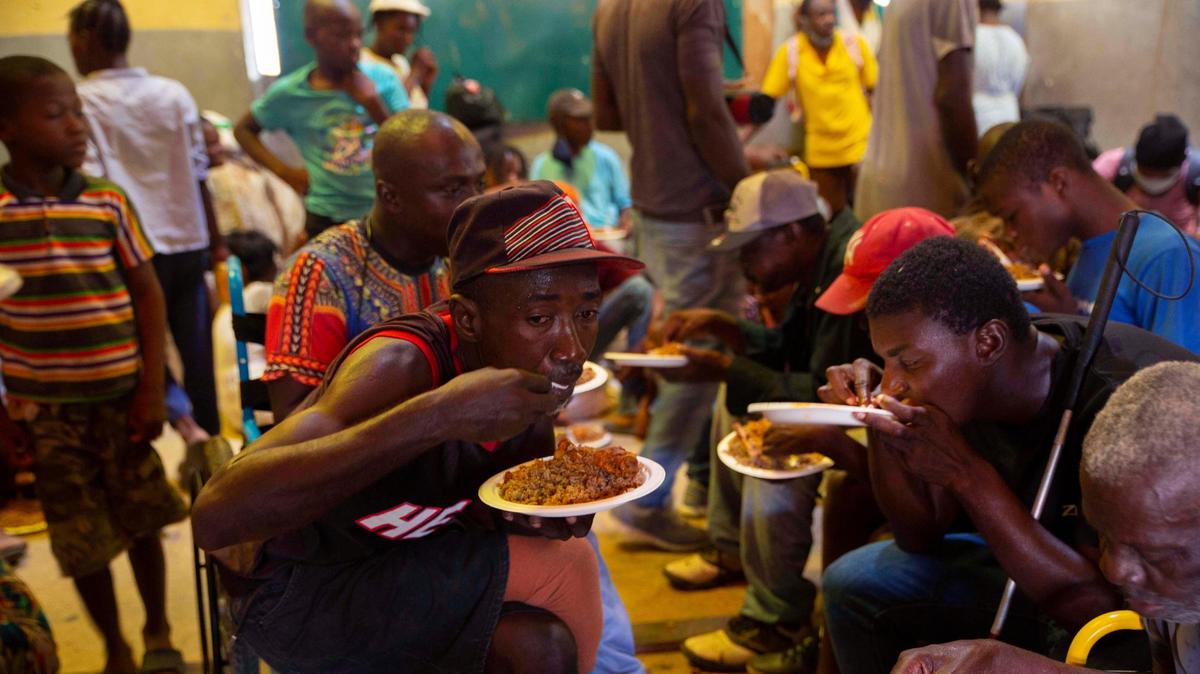 In 2021, Haitians eat in a shelter for refugees a week after armed gangs set their homes on fire in Port-au-Prince.