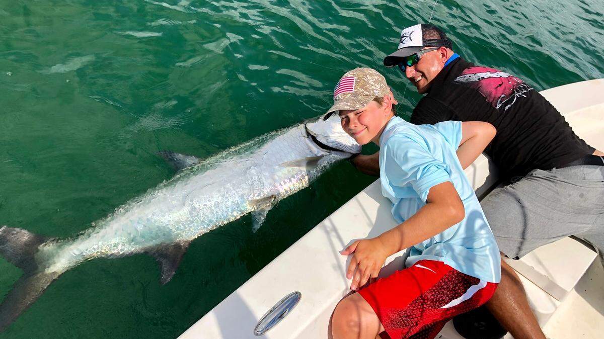 Capt. David Cohen, right, prepares to release a 100-pound tarpon caught by 12-year-old Nick Eberhart in North Biscayne Bay. Fishing for tarpon and snook has been excellent in the bay thanks to the earlier-than-usual fall mullet run.