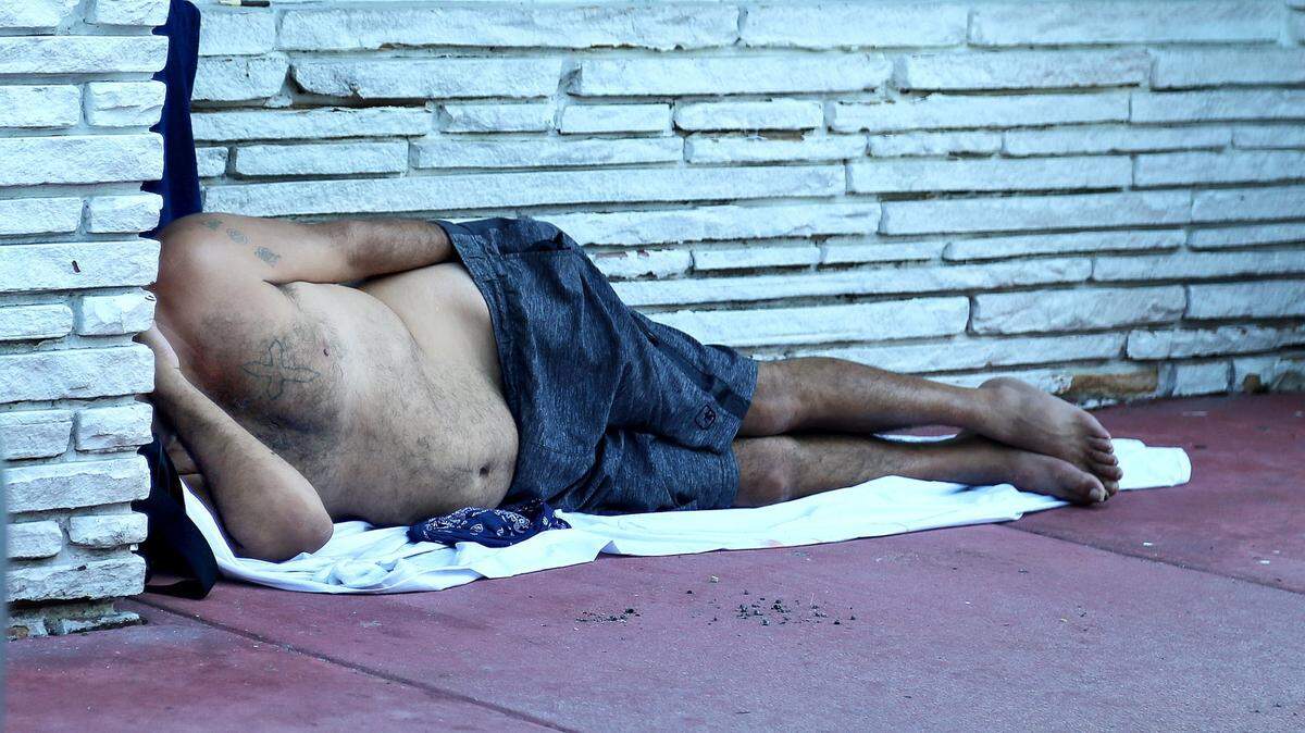 A homeless man sleeps on the sidewalk on Pennsylvania Avenue and Lincoln Road in Miami Beach in August 2020.