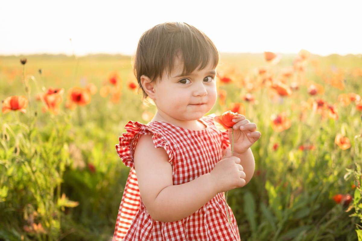 little girl holding red flower