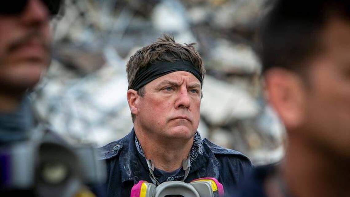 A member of a search-and-rescue team stands with colleagues during a moment of prayer at the site of the condo collapse in Surfside in June 2021.