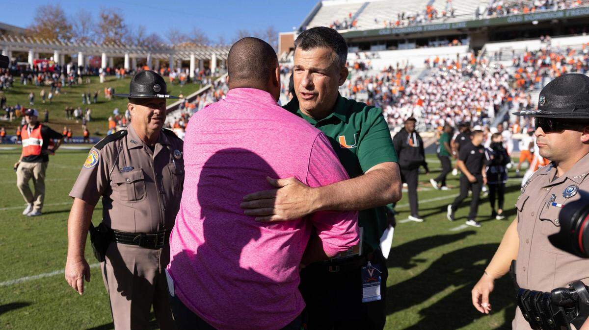 Virginia head coach Tony Elliott and Miami head coach Mario Cristobal embrace after an NCAA college football game in Charlottesville, Va. on Saturday, Oct. 29, 2022. (Mike Kropf/The Daily Progress via AP)